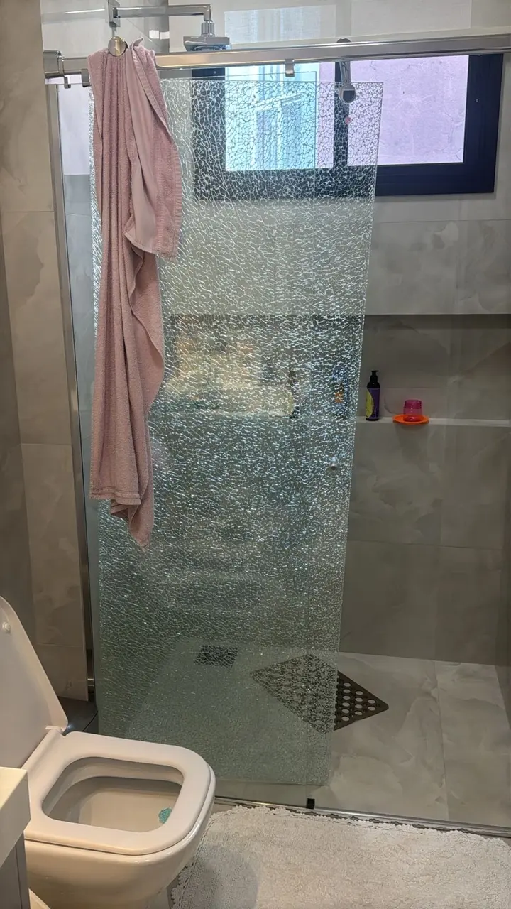 Box de banheiro quebrado com os estilhaços presos pela película de segurança